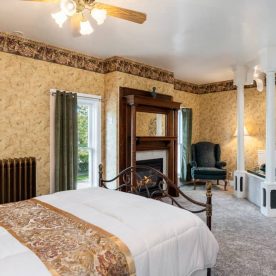 Spacious room with a queen bed with carpet flooring, a fireplace, and a two-person jetted tub